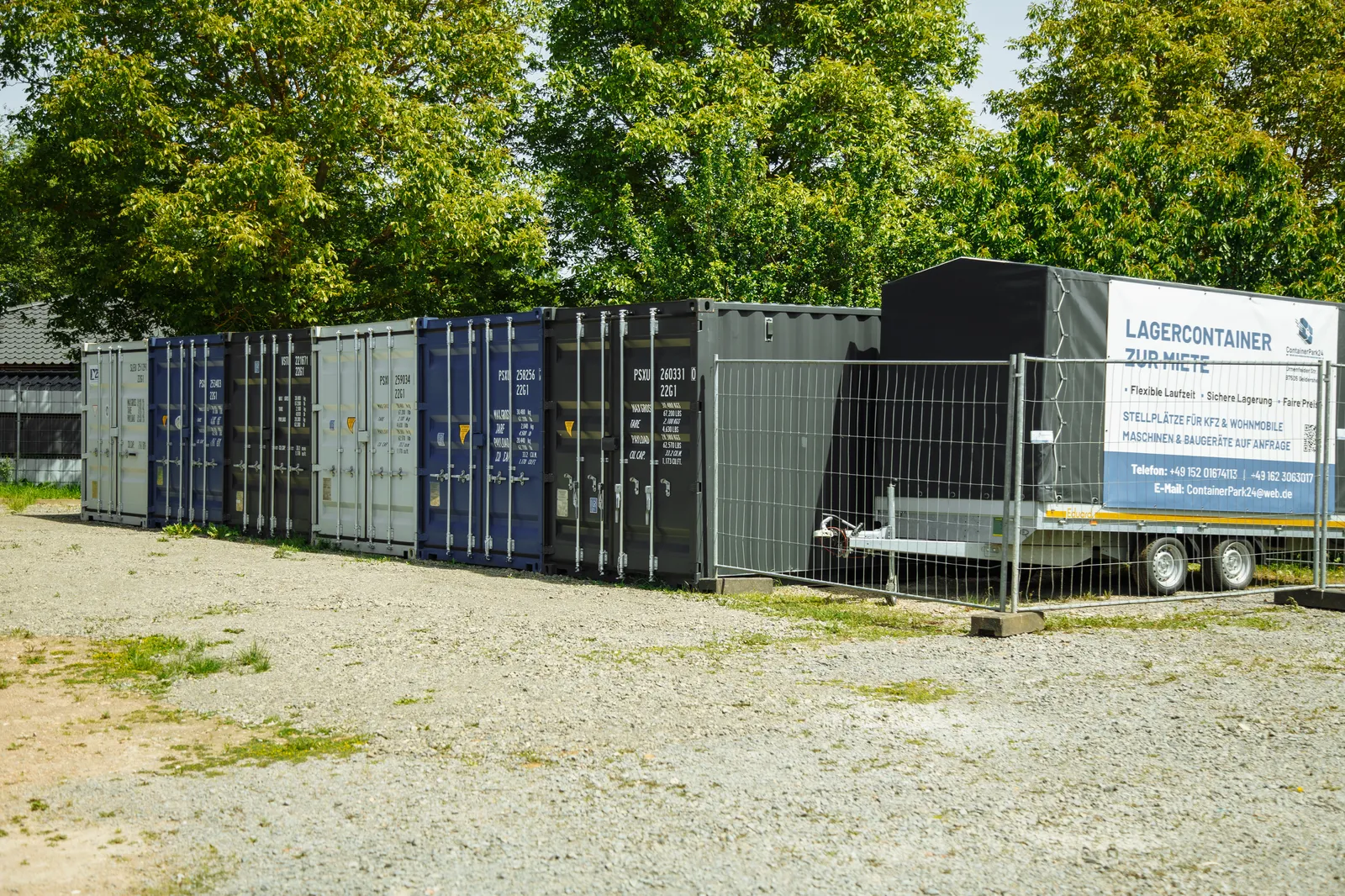 Containerreihe mit Werbeschild und Kontaktinformationen.